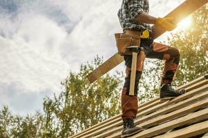 Gebäude Konstruktion Seite? ˅ Dach Arbeiter mit ein Planke im seine Hände foto