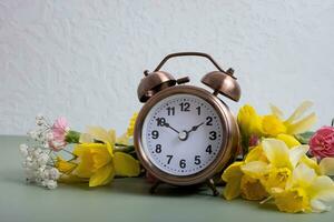 Alarm Uhr mit Frühling Blumen. Frühling Zeit, Tageslicht Ersparnisse Konzept, Frühling nach vorne foto