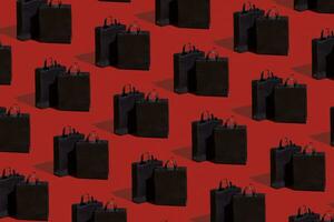 schwarz Papier Einkaufen Taschen Muster auf rot Hintergrund. schwarz Freitag Verkauf, Einkaufen Konzept. foto