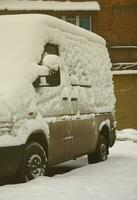 Fragment des Autos unter einer Schneeschicht nach einem starken Schneefall. Die Karosserie des Autos ist mit weißem Schnee bedeckt foto