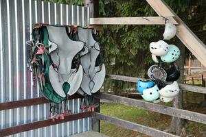 Klettern Ausrüstung - - bunt Helme und Sicherheit Westen hängend auf ein Tafel im ein Seil Park foto
