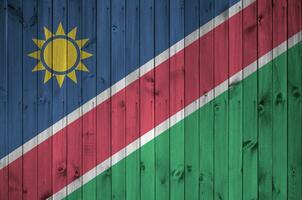 Namibia Flagge abgebildet im hell Farbe Farben auf alt hölzern Mauer. texturiert Banner auf Rau Hintergrund foto