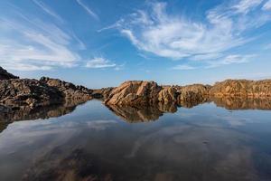 das Meerwasser zwischen den Meeresriffen reflektiert die gelben Riffe und den blauen Himmel foto