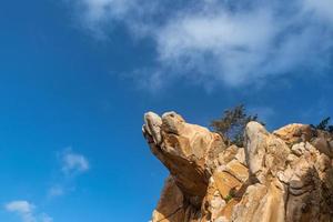 Steine in verschiedenen Formen, verwittert vom Meer unter blauem Himmel foto