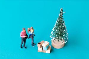 Miniaturmenschen, glückliche Familie, die neben einem Weihnachtsbaum steht