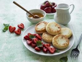 Quarkpfannkuchen, Ricotta-Krapfen auf Keramikplatte mit frischer Erdbeere.