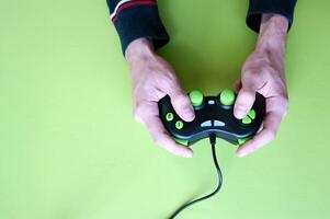 männlich Hände halt ein Gamepad im Licht Grün Hintergrund. foto