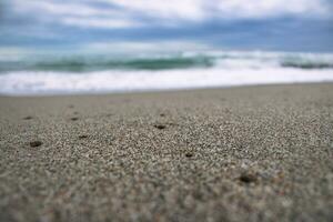 schließen oben Meer Sand Strand mit Schaum und Wellen Foto. Sand Strand Oberfläche mit selektiv Fokus. foto