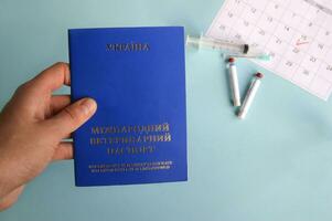 Blau Ukraine Veterinär Haustier Reisepass, Spritze und Ampulle mit Flüssigkeit auf ein Licht Blau Hintergrund foto