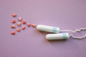 Menstruation- Tampons mit bestreut Herzen auf ein lila Hintergrund. foto