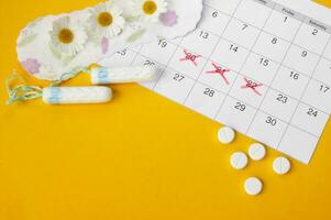 Menstruation- Pads und Tampons auf Menstruation Zeitraum Kalender mit Kamille auf Gelb Hintergrund. foto