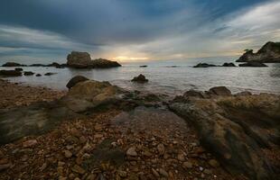 felsig Strand mit Felsen und Wasser beim Sonnenaufgang foto