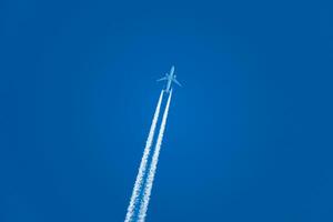 Flugzeug und es ist Kondensation Pfad, Wolke Bildung beim das zurück von ein Ebene, perfekt Blau Himmel foto