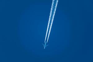 Flugzeug und es ist Kondensation Pfad, Wolke Bildung beim das zurück von ein Ebene, perfekt Blau Himmel foto