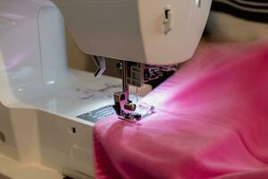 Mann mit ein Nähen Maschine mit ein Rosa Kleidungsstück, zum Reparatur arbeiten, Anpassung, Schaffung, Upcycling foto