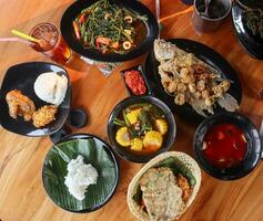 Sundanesisch Restaurant Speisekarte, Westen Java, Indonesien. sauer Gemüse, gebraten Gurami, Grünkohl und Reis. auf hölzern Tisch. foto