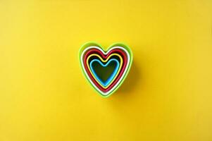 Plastik Formen von multi Farben zum Herstellung Kekse im das gestalten von ein Herzen auf ein Gelb Hintergrund. foto