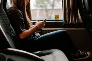 Nahaufnahme einer Dame in einem Bus mit ihrem Telefon