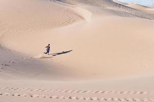 Hochwinkelaufnahme einer Frau, die auf Sanddünen in einer Wüste läuft foto