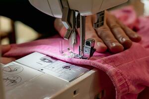 Mann mit ein Nähen Maschine mit ein Rosa Kleidungsstück, zum Reparatur arbeiten, Anpassung, Schaffung, Upcycling foto