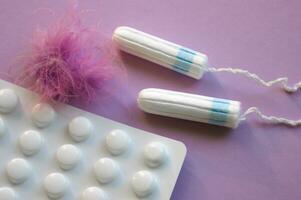 Menstruation- Tampons und Tabletten auf lila Hintergrund. foto