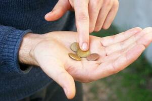 Hände von ein jung Mann Nahaufnahme, Zählen ein Kleinigkeit, Eisen Münzen Geld von Ukraine. foto