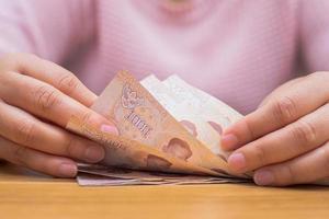 Nahaufnahme der asiatischen Frau mit dem Taschenrechner, der money.woman zählt, die Ausgaben zu Hause berechnen. foto