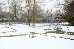 Kinder- Spielplatz im Winter unter Schnee. schwingen, Karussell und gleiten. Winter Verwüstung foto