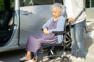 Pflegekraft Hilfe und Unterstützung asiatisch Alten Frau Sitzung auf Rollstuhl bereiten erhalten zu ihr Auto zu Reise im Urlaub. foto