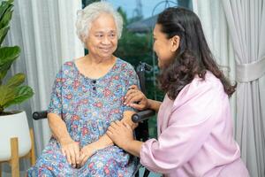 Pflegekraft Hilfe asiatisch Senior Frau auf Rollstuhl mit Liebe beim heim. foto