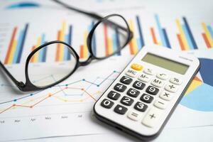 Brille mit Taschenrechner auf Diagramm Graph Papier. Finanzen, Konto, Statistik, Investition Daten Wirtschaft, Lager Austausch Geschäft. foto