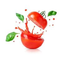 Spritzen von Tomatensaft mit fliegenden Basilikumblättern isoliert auf weißem Hintergrund. Gestaltungselement für Produktetikett.