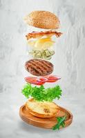 fliegender Hamburger auf grauem Betonhintergrund. Fast-Food-Konzept
