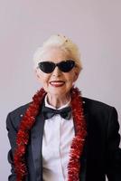 Schöne, stilvolle, reife ältere Frau in Sonnenbrille und Smoking, die das neue Jahr feiert. Spaß, Party, Stil, Feierkonzept foto