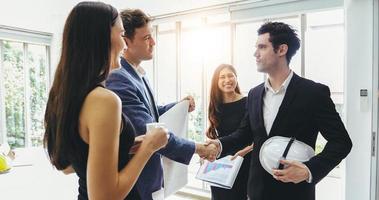 Geschäftsleute, die sich die Hände schütteln und ihre Zustimmung zur Vertragsunterzeichnung und zum Abschluss eines Meetings lächeln foto