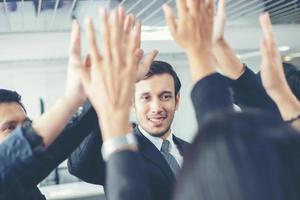 glückliche geschäftsleute, die teamarbeit zeigen und fünf geben, nachdem sie eine vereinbarung oder einen vertrag mit ausländischen partnern im bürointerieur unterzeichnet haben. foto