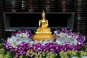 Gold Buddha Statue schmücken umgeben Vielfalt Farbe Orchideen zum Gießen Wasser auf Tabelle draussen im Songkran Festival im Thailand. foto