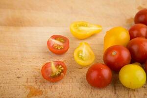 rot und Gelb Kirsche Tomaten auf ein hölzern Schneiden Tafel foto