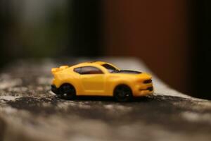 Foto von ein Gelb Spielzeug Auto mit ein verschwommen Hintergrund.