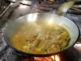 das Prozess von Kochen Rendang oder Rindfleisch und Hähnchen Curry mit das traditionell Methode, Kochen mit Brennholz foto