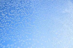 abstrakt Winter Hintergrund. Frost auf ein gefroren Fenster gegen das Blau Himmel. foto