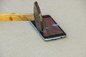 Hammer und Smartphone. das Bildschirm von das Smartphone, ein gebrochen Ha foto