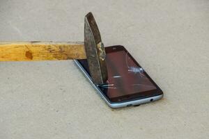 Hammer und Smartphone. das Bildschirm von das Smartphone, ein gebrochen Ha foto