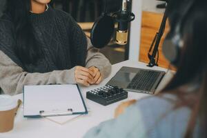 frau, die einen podcast auf ihrem laptop mit kopfhörern und einem mikroskop aufnimmt. weiblicher podcaster, der audio-podcast von ihrem heimstudio macht. foto