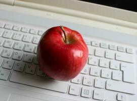 verschwommen Tasten von Weiß Tastatur mit saftig rot Apfel Obst auf es foto