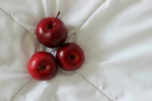 drei rot saftig Äpfel auf ein Weiß Stoff oben Aussicht Lager Foto