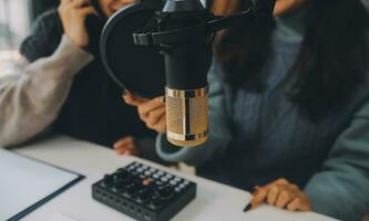frau, die einen podcast auf ihrem laptop mit kopfhörern und einem mikroskop aufnimmt. weiblicher podcaster, der audio-podcast von ihrem heimstudio macht. foto