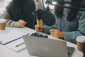 frau, die einen podcast auf ihrem laptop mit kopfhörern und einem mikroskop aufnimmt. weiblicher podcaster, der audio-podcast von ihrem heimstudio macht. foto