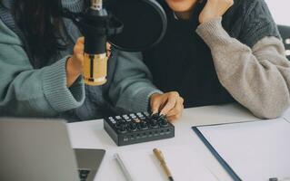 frau, die einen podcast auf ihrem laptop mit kopfhörern und einem mikroskop aufnimmt. weiblicher podcaster, der audio-podcast von ihrem heimstudio macht. foto