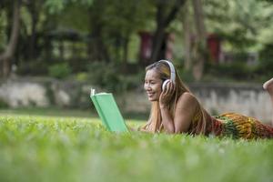asiatische Frau hört Lieblingsmusik über Kopfhörer und liest ein Buch. glückliche Zeit und entspannen.